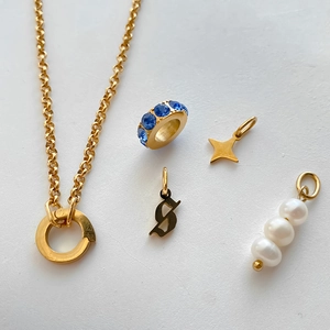 Close-up of gold plated stainless steel charms including pearls, stars and blue rhinestones
