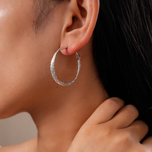 Dettaglio di orecchini a cerchio geometrici minimalisti in argento su una modella