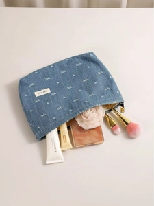 Blue denim makeup bag with white bow embroidery and zipper closure for travel