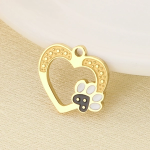 Macro shot of gold heart pendant with black and white paw prints on beige textured fabric