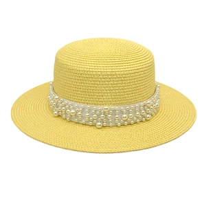 Détail d'un chapeau de soleil en paille jaune avec ruban de dentelle et perles