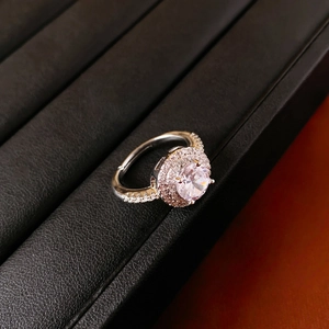 Gros plan sur une bague géométrique argentée avec zircon brillant et sertissage double halo