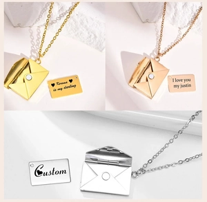 Detailed view of 18k gold heart-sealed envelope necklaces with customizable metal cards