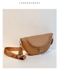 Detail of brown textured leather crescent bag with dual silver zippers and wide strap