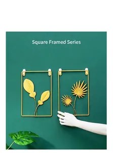 Detail showing golden metal feather and palm leaf wall art in rectangular frames