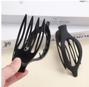Detail of a matte black oval hair claw clip being held to show the smooth texture and grip
