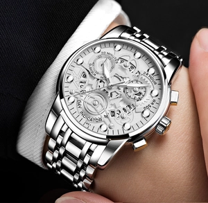 Close-up of a silver mechanical watch with hollow dial and steel strap on a male wrist