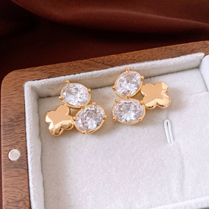 Detailaufnahme der 18K vergoldeten Blumenohrringe mit weißen ovalen Schmucksteinen