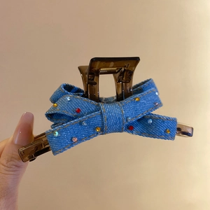 Detail of brown resin shark clip with blue denim bow and multi-colored rhinestones
