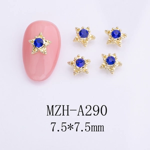 Detail of star-shaped gold nail charms with blue rhinestones and bead accents