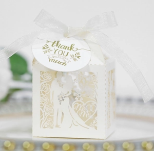 Close-up of white laser-cut Mr & Mrs wedding candy box with ribbon and thank you tag