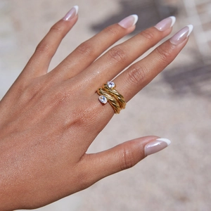 Close-up of golden twist rope ring featuring two pear-cut crystals on a hand
