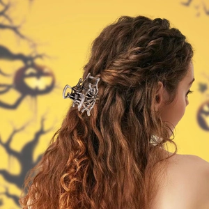 Pince à cheveux araignée en métal pour Halloween portée sur cheveux longs avec fond citrouille
