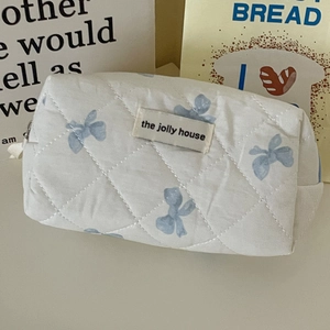 Dettaglio della borsa per cosmetici trapuntata con fiocchi blu ed etichetta Jolly House
