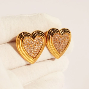 Élégantes boucles d'oreilles cœur en or avec zircons pavés sur des gants blancs de luxe