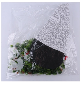 Close-up of Christmas wreath with pine needles, red berries and gnome textile hat detail