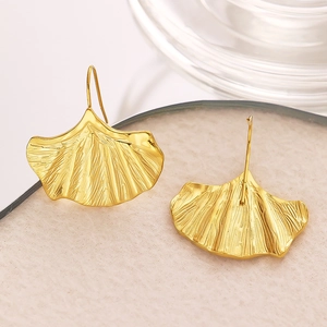 Détail rapproché de boucles d'oreilles ginkgo dorées avec texture fine et crochet élégant