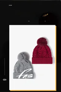 Detail of cable knit texture and large pom-pom on winter beanies in burgundy and grey