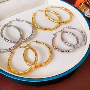 Boucles d'oreilles créoles texturées en or et argent présentées dans un écrin à bijoux