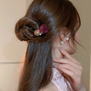 Dettaglio del fermaglio per capelli con rosa rossa e perla per uno stile vintage elegante