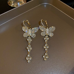 Detail of gold butterfly tassel earrings with sparkling rhinestones and small pearls