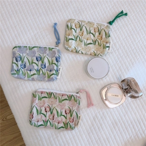 Detailed view of three floral cotton pouches for coins and earphones in pastel colors