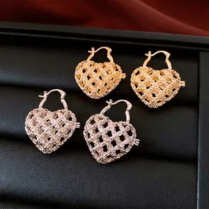 Luxe hollow heart woven hoop earrings in gold and silver finish on black leather tray
