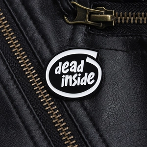 Détail d'un pin's émaillé dead inside fixé sur une veste en cuir noir texturé