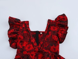 Macro detail of V-neckline with ruffle sleeves and red floral jacquard fabric texture
