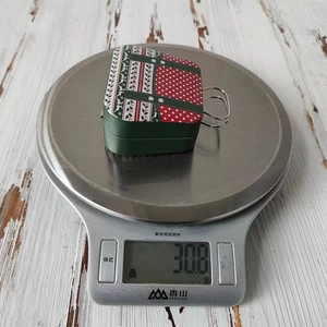 Detailed top view of a Christmas tin suitcase candy box weighing 30.8g on a digital scale