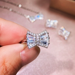 Silver bow ring with sparkling zircons part of a jewelry set shown on a pink background