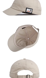 Detail view of cotton texture, decorative patch and metal buckle on beige short brim cap