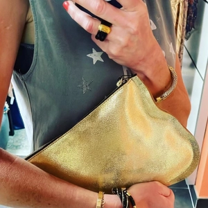 Elegant gold irregular heart-shaped clutch bag with metallic finish held by model