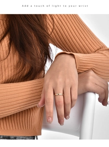 Macro detail of minimalist 18K gold plated ring with sparkling zircons on finger