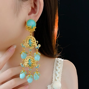 Macro shot of vintage gold flower drop earrings with turquoise stones and blue crystals