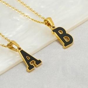 Gold stainless steel initial necklaces with black enamel letters A and B on marble
