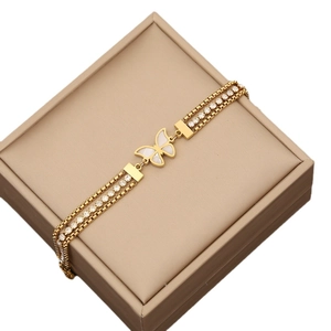 Three-layer golden butterfly bracelet with white zircon stones on a jewelry box