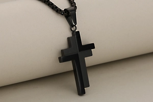 Macro shot of minimalist black stainless steel cross pendant with black box chain detail
