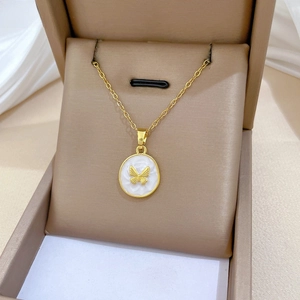 Macro view of gold butterfly oval pendant with white enamel inlay on jewelry box