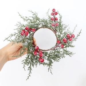 Detail of snowy cypress branch candle ring with festive red berries on white background