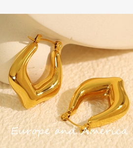 Macro shot of gold-plated chunky C-shape hoop earrings with irregular geometric texture