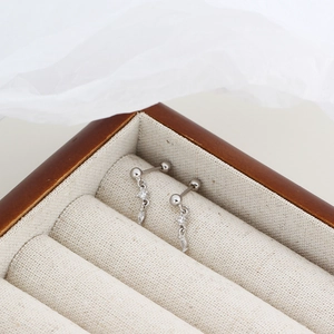 Detail of silver S925 drop earrings with crystal charms on a wooden jewelry box