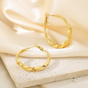 Elegant 18K gold-plated twisted C-shape hoop earrings displayed on beige silk and stone