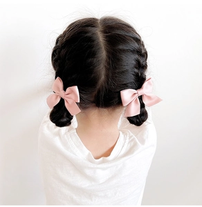 Paire de barrettes à nœuds en satin rose pour filles sur une coiffure tressée
