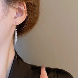 Close-up of elegant long silver drop earrings with zircons on a female model