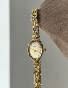 Vue détaillée du cadran ovale champagne avec chiffres romains et bracelet chaîne doré