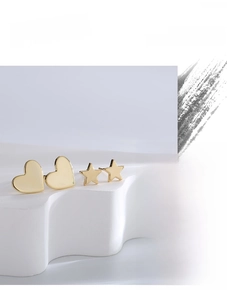 Artistic layout of gold heart and star stud earrings set on white geometric stands