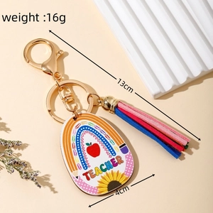 Macro view of a teacher keychain with rainbow wood tag, golden clasp, and colorful tassel