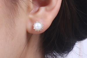 Detail shot of a natural white pearl earring with a halo of zircon on a golden base