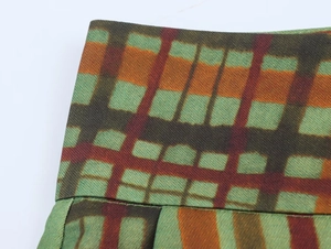 Dettaglio ravvicinato del motivo a quadri verde e arancio su tessuto twill operato
